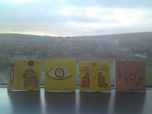 Here are the clay tiles nearly completely painted, displayed in the window of the art room where i taught in 2013